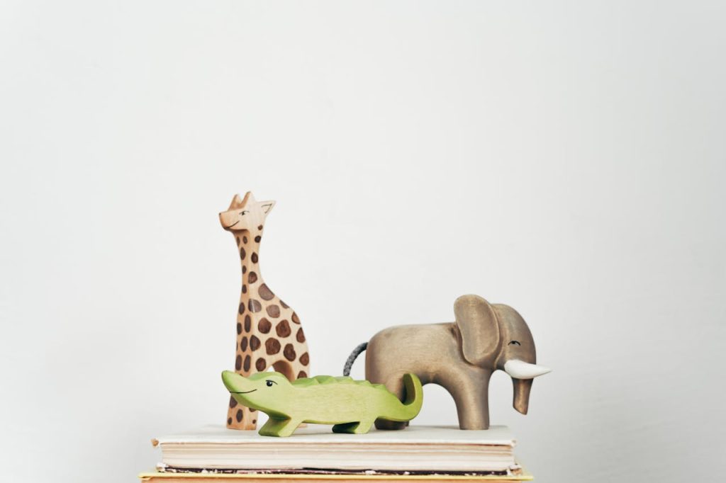 A close-up of wooden giraffe, elephant, and crocodile figurines stacked on books.